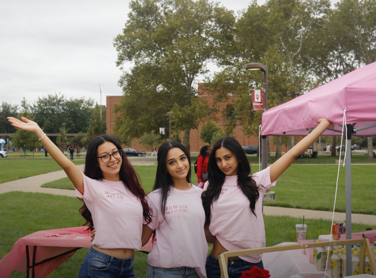 Three members in Her Health Her Future shirts at the IU Indy pop-up